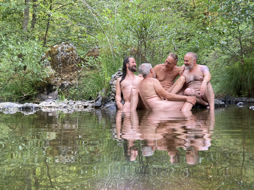 four men sitting in a river pool talking